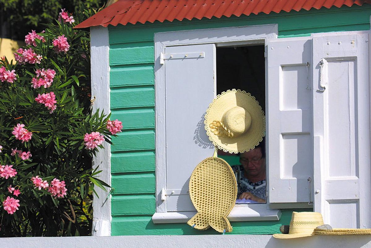 Case créole verte de Corossol, chapeaux de paille à la fenêtre